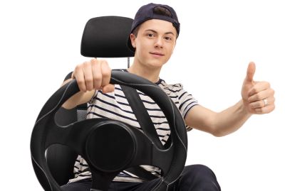 Teenager seated in car seat giving thumb up